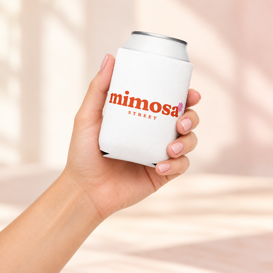 Lifestyle mockup of a woman holding the white Mimosa Street can cooler with centered orange logo and pink flower